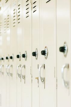 a row of white lockers with black handles