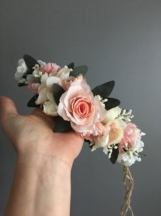 a hand holding a bouquet of flowers on top of a gray background with white and pink blooms