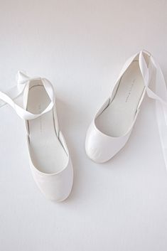 two pairs of white shoes tied together with a ribbon on the bottom one pair has a bow at the top