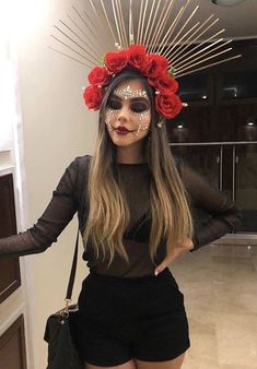 a woman with makeup and flowers on her head standing in a hallway wearing black shorts