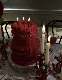 a red cake sitting on top of a table next to candles and other decor items