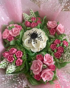 a bouquet of pink and white flowers with green leaves on it's centerpiece