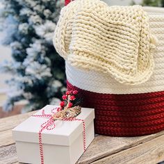 two knitted baskets sitting on top of a wooden table next to a christmas tree