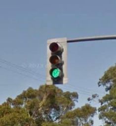 a traffic light that is green on a pole with trees in the backround