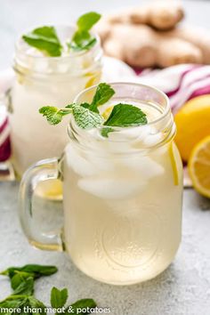 two mason jars filled with lemonade and mint garnish next to sliced ginger