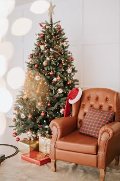 a living room with a christmas tree in the corner and a leather chair next to it