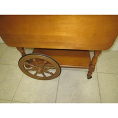 an old wooden table with wheels on the bottom and sides, sitting on tile flooring