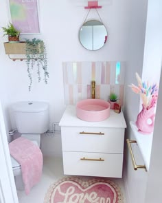 a white bathroom with pink accents on the vanity and rug in front of the sink