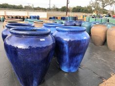 several large blue vases sitting on top of a cement floor next to each other