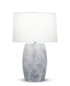 a lamp with a white shade on it and a gray vase in the foreground