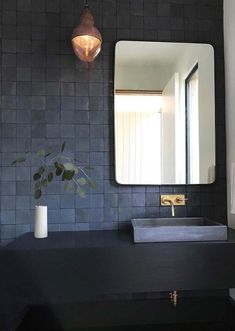 a bathroom sink sitting under a mirror next to a vase with a plant in it