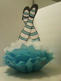 a paper doll sitting on top of a white table next to a blue flower pot