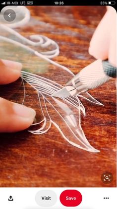 someone using scissors to cut paper on a wooden table