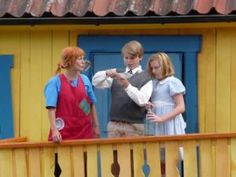 three children are standing on the balcony and one is pointing at something in front of them