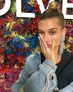 a woman with her hand on her face in front of a colorful background and flowers