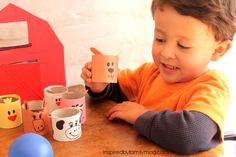 a little boy that is sitting at a table with some paper cups in front of him