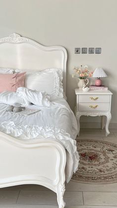 a white bed sitting in a bedroom on top of a hard wood floor next to a rug