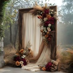 an outdoor wedding arch decorated with dried flowers and pamonini, grass and feathers