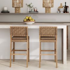 two chairs and a bowl of fruit on a counter top in a kitchen with white walls