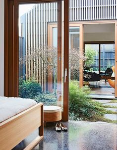 an open bedroom with sliding glass doors leading to the patio and garden area in front of it