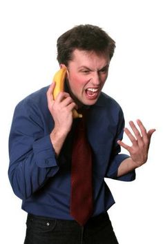 a man holding a banana up to his ear and talking on the phone while wearing a tie