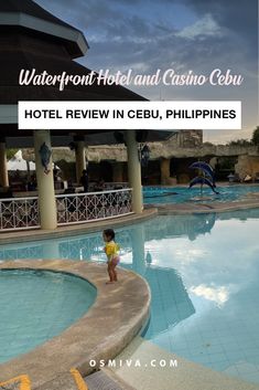 a small child standing in the middle of a swimming pool next to a hotel and casino