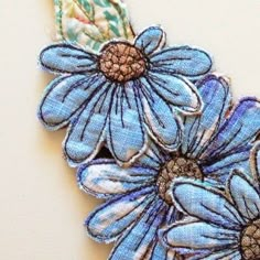 three blue flowers are sitting on a piece of fabric