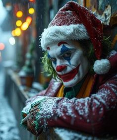 a man dressed as a clown standing in the snow with his arms crossed and face painted red, white and blue