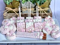 pink and white desserts are arranged on a platter with flowers in the background