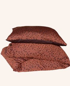 two pillows on top of each other in front of a white background with black dots