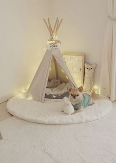 a small dog sitting in front of a teepee with lights on it's sides