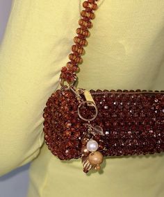 a woman wearing a brown beaded purse with a chain attached to the back of it