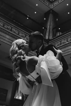 a bride and groom kissing in front of a chandelier