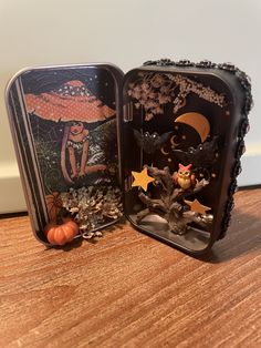 two tins with halloween decorations in them sitting on a table next to each other