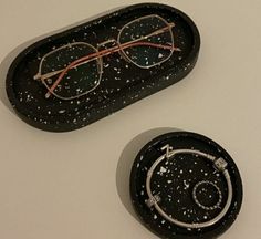 two glasses sitting on top of a black tray with speckles and metal frames