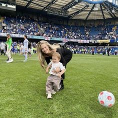 a woman holding a baby next to a soccer ball