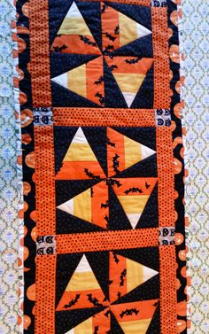 an orange and black quilt with bats on it