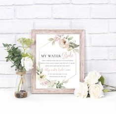 a white framed sign with flowers and greenery on it next to a vase filled with roses