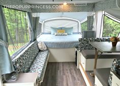 the inside of a camper with a bed, couch and table next to it