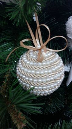 an ornament hanging from a christmas tree decorated with white pearls and brown ribbon