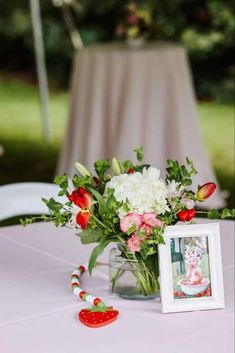 a vase filled with flowers on top of a table next to a small photo frame