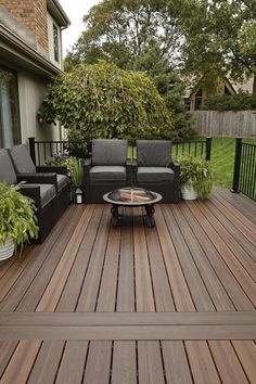 a wooden deck with black furniture and potted plants