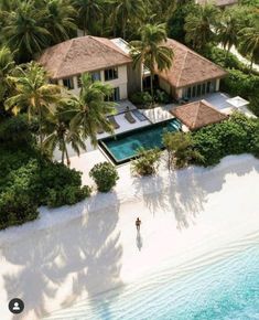 an aerial view of a beachfront home surrounded by palm trees and blue ocean water