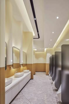 a row of urinals in a bathroom with sinks and mirrors on the wall