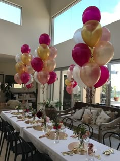 a long table is set up with balloons and place settings for an elegant dinner party