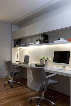 a desk with two chairs and a computer on top of it in an office setting