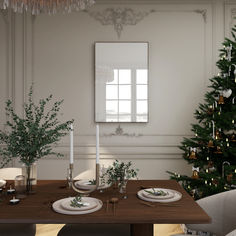 a dining room table set for two with place settings and christmas tree in the background