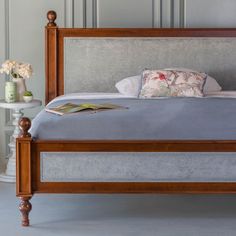 a bed with wooden headboard and foot board in a white room next to a wall