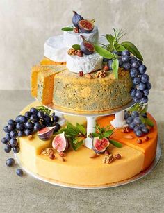 three tiered cheese cake with figurines and fruits on top, sitting on a marble countertop