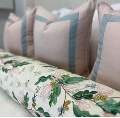 four pink and blue pillows sitting on top of a bed